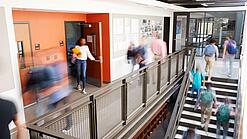 Schülerinnen und Schüler sind unterwegs in einem Schulgebäude.