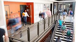 Schülerinnen und Schüler sind unterwegs in einem Schulgebäude.
