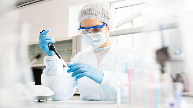 Junge Frau in Laborkleidung arbeitet in einem Labor.