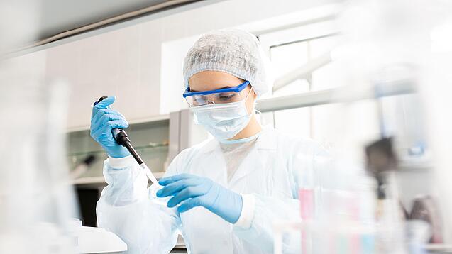 Junge Frau in Laborkleidung arbeitet in einem Labor.