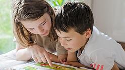 Zwei Kinder lesen in einem Buch.