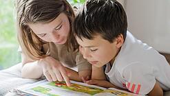 Zwei Kinder lesen in einem Buch.