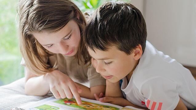 Zwei Kinder lesen in einem Buch.
