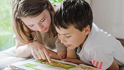 Zwei Kinder lesen in einem Buch.