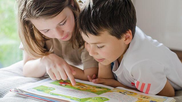Zwei Kinder lesen in einem Buch.