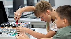 Zwei Jungen sind mit Technik beschäftigt.