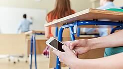 Schüler benutzt Handy im Unterricht.