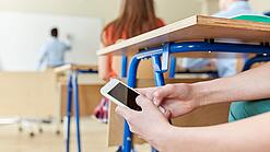Schüler benutzt Handy im Unterricht.