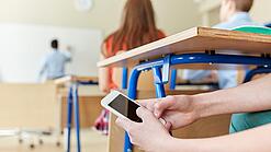 Schüler benutzt Handy im Unterricht.