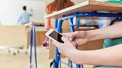 Schüler benutzt Handy im Unterricht.