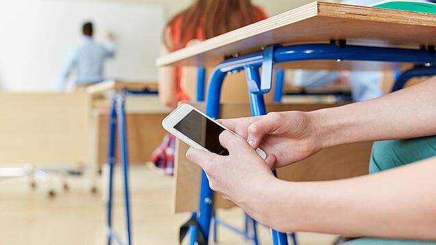 Schüler benutzt Handy im Unterricht.