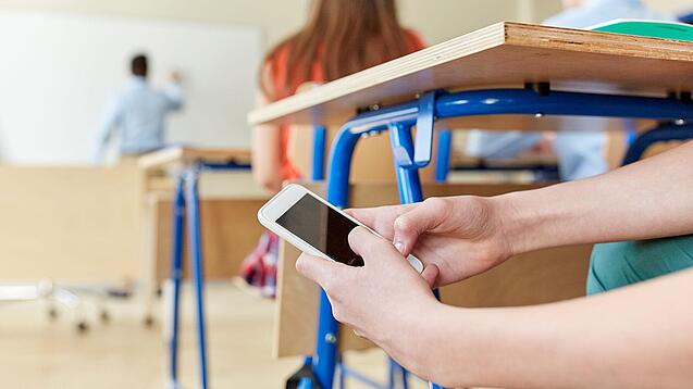 Schüler benutzt Handy im Unterricht.