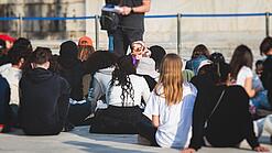 Gruppe junger Menschen sitzt auf dem Boden und hört sich einen Vortrag an