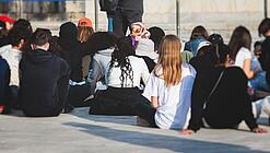 Gruppe junger Menschen sitzt auf dem Boden und hört sich einen Vortrag an