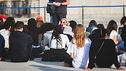 Gruppe junger Menschen sitzt auf dem Boden und hört sich einen Vortrag an