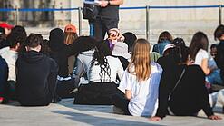 Gruppe junger Menschen sitzt auf dem Boden und hört sich einen Vortrag an