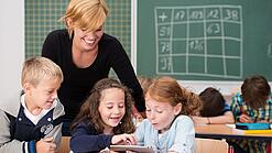 Lehrerin und Grundschüler:innen in einem Klassenraum.
