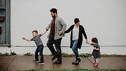Zwei Erwachsene und zwei Kinder halten sich an den Händen.