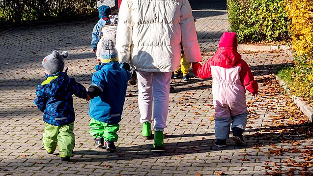 Eine erwachsene Person hat mehrere Kindergartenkinder an der Hand.