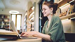 Eine Studentin arbeitet an einem Laptop in einem Cafe.