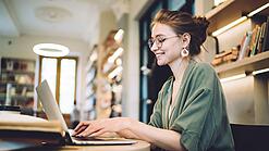 Eine Studentin arbeitet an einem Laptop in einem Cafe.