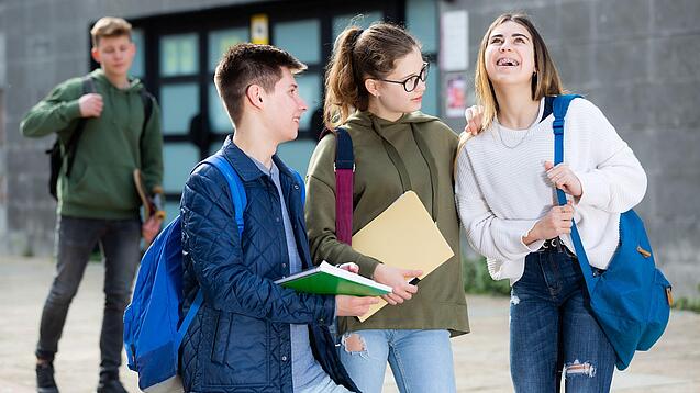 Gruppe von Jugendlichen vor einem Schulgebäude.