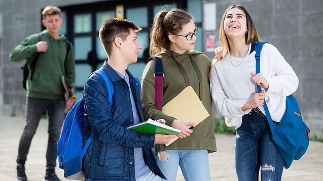 Gruppe von Jugendlichen vor einem Schulgebäude.