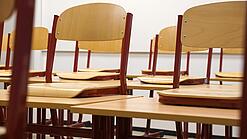 Ein Klassenzimmer, in dem die Stühle auf die Tische hochgestellt sind.