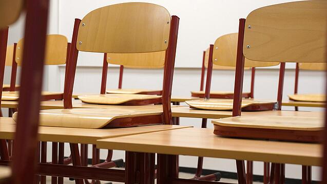 Ein Klassenzimmer, in dem die Stühle auf die Tische hochgestellt sind.