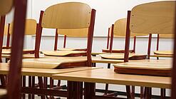 Ein Klassenzimmer, in dem die Stühle auf die Tische hochgestellt sind.