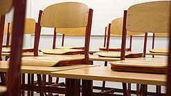 Ein Klassenzimmer, in dem die Stühle auf die Tische hochgestellt sind.