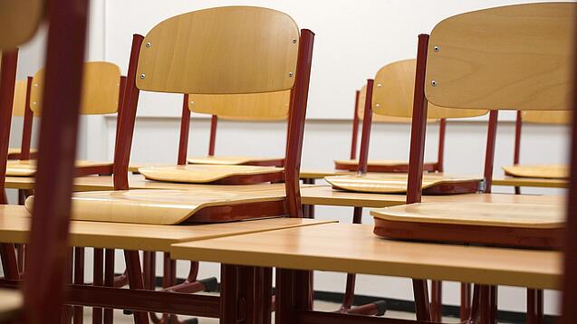 Ein Klassenzimmer, in dem die Stühle auf die Tische hochgestellt sind.