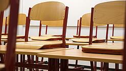 Ein Klassenzimmer, in dem die Stühle auf die Tische hochgestellt sind.