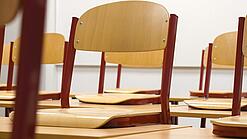 Ein Klassenzimmer, in dem die Stühle auf die Tische hochgestellt sind.