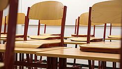 Ein Klassenzimmer, in dem die Stühle auf die Tische hochgestellt sind.