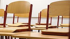 Ein Klassenzimmer, in dem die Stühle auf die Tische hochgestellt sind.
