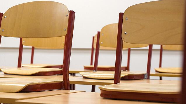 Ein Klassenzimmer, in dem die Stühle auf die Tische hochgestellt sind.