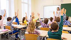 Eine Lehrerin steht vor einer Schulklasse. 