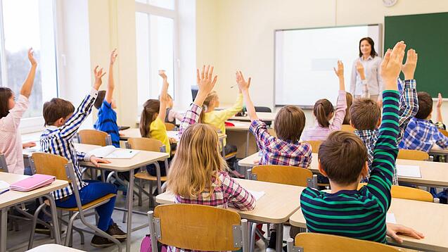 Eine Lehrerin steht vor einer Schulklasse. 