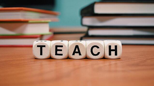 Buchstabenbauklötze bilden das Wort "Teach".