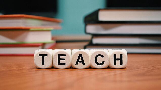 Buchstabenbauklötze bilden das Wort "Teach".