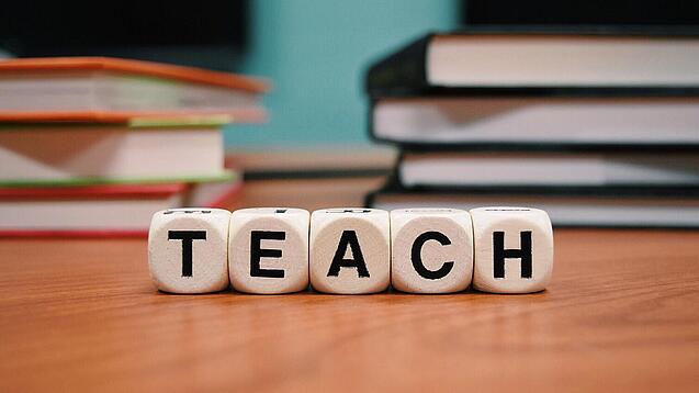 Buchstabenbauklötze bilden das Wort "Teach".