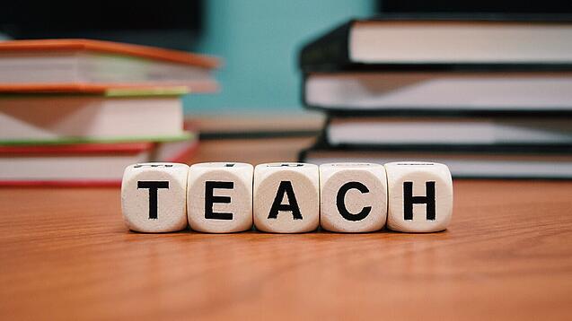 Buchstabenbauklötze bilden das Wort "Teach".