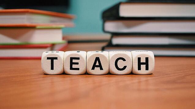 Buchstabenbauklötze bilden das Wort "Teach".