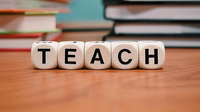 Buchstabenbauklötze bilden das Wort "Teach".