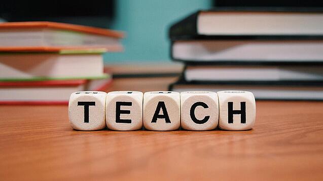 Buchstabenbauklötze bilden das Wort "Teach".