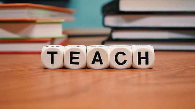 Buchstabenbauklötze bilden das Wort "Teach".