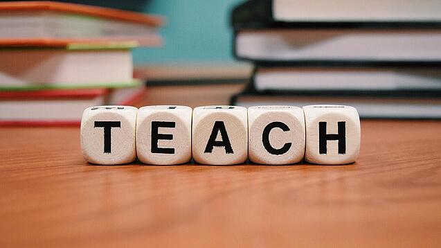 Buchstabenbauklötze bilden das Wort "Teach".