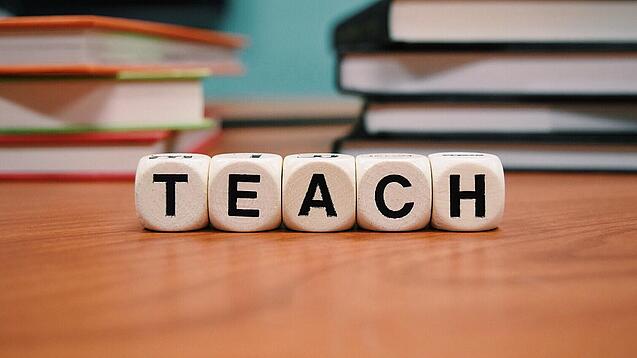 Buchstabenbauklötze bilden das Wort "Teach".