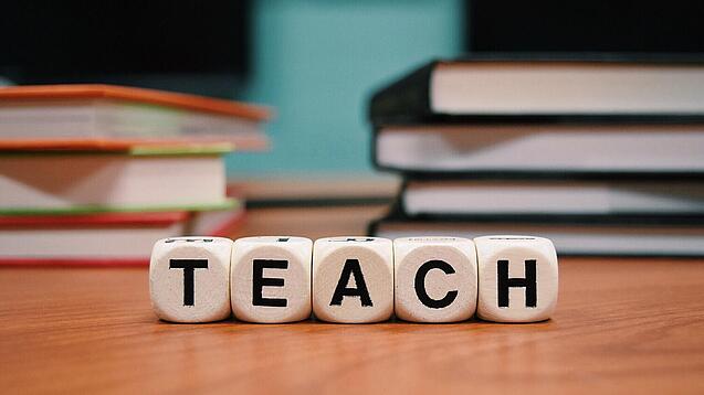 Buchstabenbauklötze bilden das Wort "Teach".